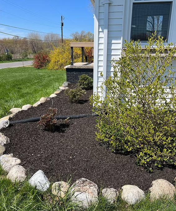 Fresh mulch beds with stone border along a home